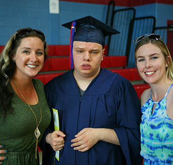 Two adults posing for a picture with a recent graduate